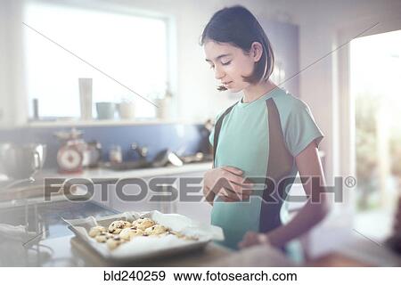 Mixed Race girl looking at tray of cookies View Large Photo Image Stock Photo - Mixed Race girl looking at tray of cookies. Fotosearch