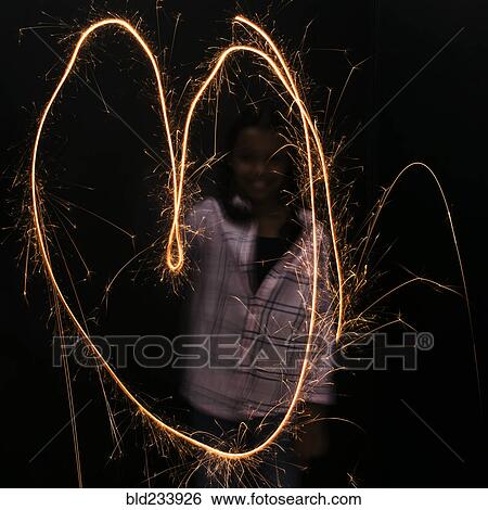 Stock Photograph - Mixed Race girl making heart-shape with sparkler. Fotosearch
