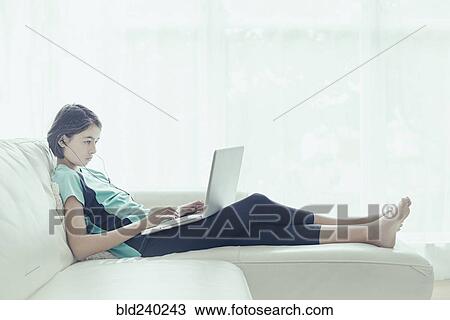 Mixed Race girl on sofa using laptop View Large Photo Image Stock Image - Mixed Race girl on sofa using laptop. Fotosearch
