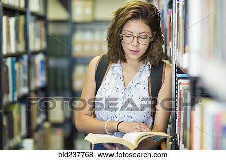 Stock Photo - Mixed Race girl reading book in library. Fotosearch