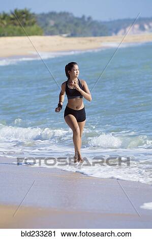 Stock Image - Mixed Race girl running on beach. Fotosearch