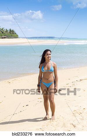 Stock Photograph - Mixed Race girl standing on beach. Fotosearch