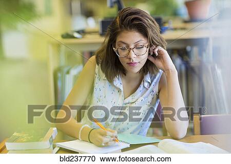 Stock Image - Mixed Race girl studying in library. Fotosearch
