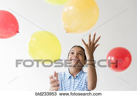 Stock Image - Mixed Race girl throwing balloons. Fotosearch