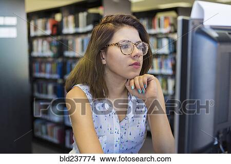 Picture - Mixed Race girl using computer in library. Fotosearch