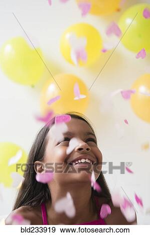 Stock Photo - Mixed Race girl watching heart-shape confetti falling. Fotosearch