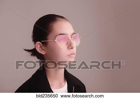 Stock Image - Mixed Race girl wearing heart-shape sunglasses. Fotosearch