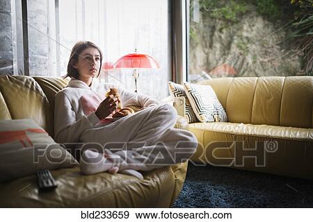 Mixed Race girl wearing rabbit costume sitting on sofa eating croissant View Large Photo Image Stock Photo - Mixed Race girl wearing rabbit costume sitting on sofa eating croissant. Fotosearch