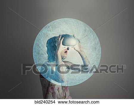 Picture - Mixed Race girl wearing virtual reality goggles in blue sphere. Fotosearch
