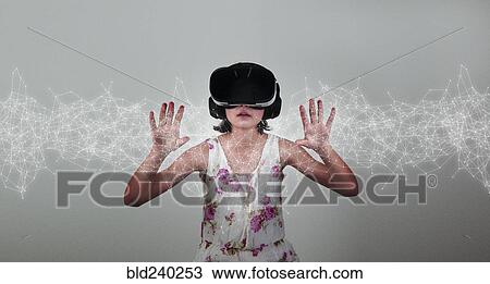 Stock Image - Mixed Race girl wearing virtual reality goggles. Fotosearch