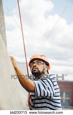 Mixed Race man climbing rock climbing wall View Large Photo Image Stock Image - Mixed Race man climbing rock climbing wall. Fotosearch