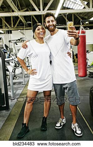 Mixed Race man couple posing for cell phone selfie in gymnasium View Large Photo Image Stock Image - Mixed Race man couple posing for cell phone selfie in gymnasium. Fotosearch