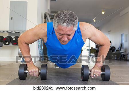 Mixed Race man doing push-ups with dumbbells in gymnasium View Large Photo Image Stock Photography - Mixed Race man doing push-ups with dumbbells in gymnasium. Fotosearch