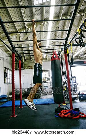 Mixed Race man hanging from bars in gymnasium View Large Photo Image Stock Photo - Mixed Race man hanging from bars in gymnasium. Fotosearch