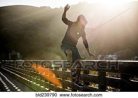 Mixed Race man jumping near railing on footbridge View Large Photo Image Stock Image - Mixed Race man jumping near railing on footbridge. Fotosearch