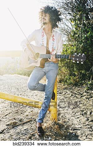 Mixed Race man leaning on gate playing guitar View Large Photo Image Picture - Mixed Race man leaning on gate playing guitar. Fotosearch