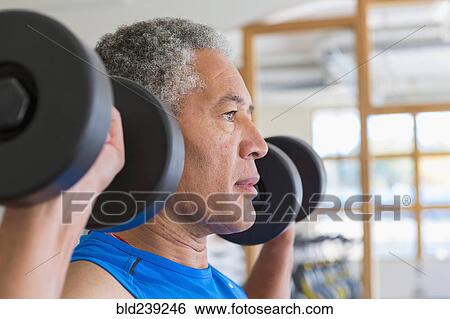 Mixed Race man lifting dumbbells in gymnasium View Large Photo Image Stock Photograph - Mixed Race man lifting dumbbells in gymnasium. Fotosearch
