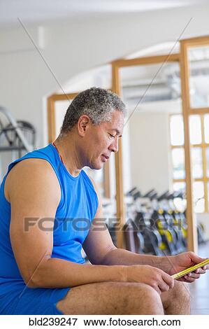 Stock Photo - Mixed Race man reading notes in gymnasium. Fotosearch