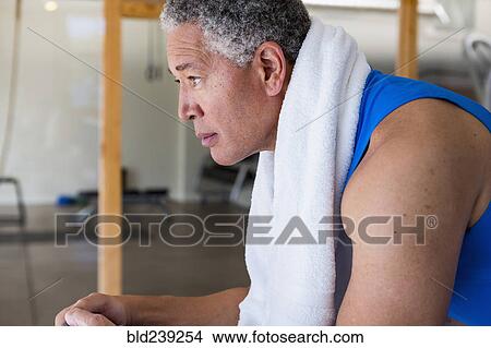 Mixed Race man resting with towel around neck during workout View Large Photo Image Picture - Mixed Race man resting with towel around neck during workout. Fotosearch