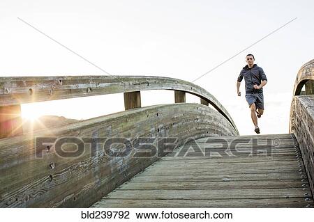 Mixed Race man running at top of curving footbridge View Large Photo Image Stock Image - Mixed Race man running at top of curving footbridge. Fotosearch