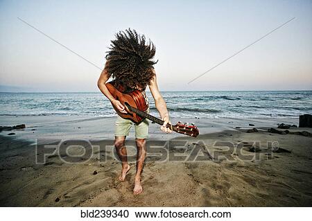 Mixed Race man tossing hair and playing guitar at beach View Large Photo Image Stock Image - Mixed Race man tossing hair and playing guitar at beach. Fotosearch