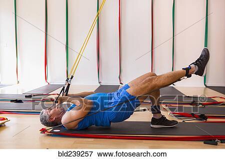 Stock Photo - Mixed Race man using resistance bands in gymnasium. Fotosearch