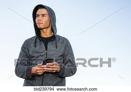 Mixed Race man wearing hoody texting on cell phone View Large Photo Image Picture - Mixed Race man wearing hoody texting on cell phone. Fotosearch