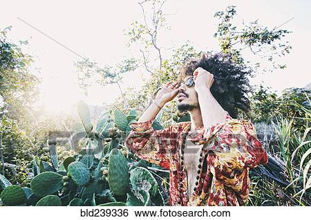 Stock Photograph - Mixed Race man wearing sunglasses near cactus. Fotosearch