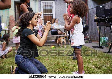 Picture - Mixed Race mother and daughter playing clapping game. Fotosearch