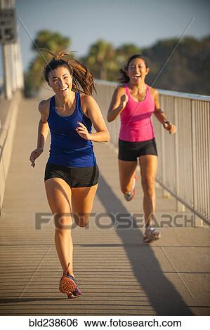 Mixed Race mother and daughter running near railing View Large Photo Image Stock Photograph - Mixed Race mother and daughter running near railing. Fotosearch
