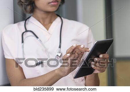 Mixed Race nurse using digital tablet View Large Photo Image Stock Photo - Mixed Race nurse using digital tablet. Fotosearch