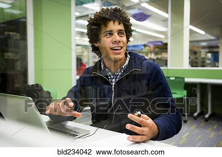 Stock Image - Mixed Race student using laptop in library. Fotosearch