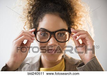 Stock Image - Mixed Race woman adjusting eyeglasses. Fotosearch