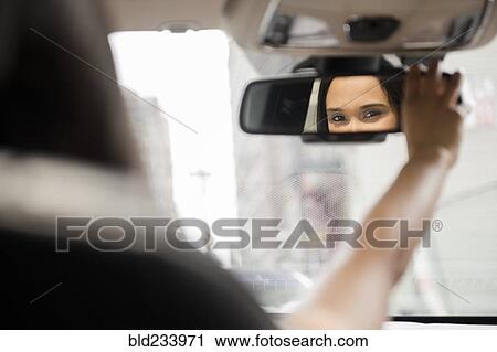 Mixed Race woman adjusting rear-view mirror in car View Large Photo Image Stock Image - Mixed Race woman adjusting rear-view mirror in car. Fotosearch