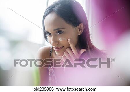Mixed Race woman applying lotion to cheek View Large Photo Image Stock Image - Mixed Race woman applying lotion to cheek. Fotosearch