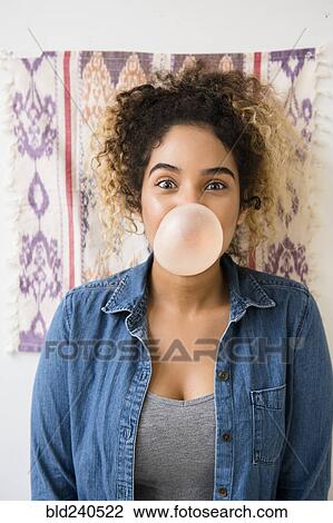 Stock Image - Mixed Race woman blowing bubble with gum. Fotosearch