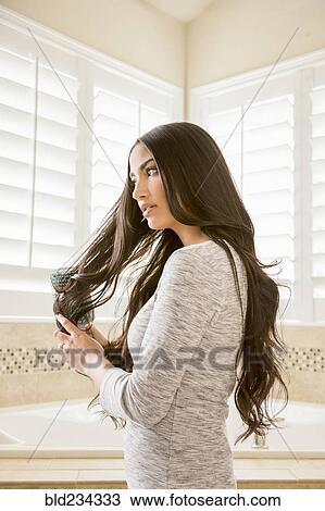Mixed Race woman brushing hair in bathroom View Large Photo Image Stock Image - Mixed Race woman brushing hair in bathroom. Fotosearch