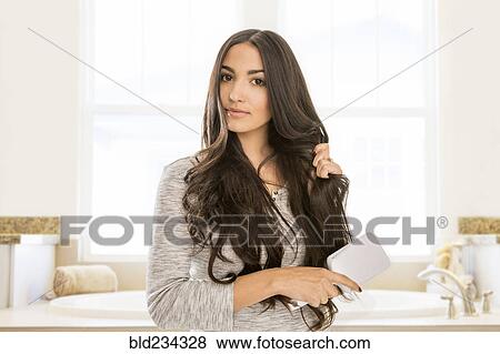 Mixed Race woman brushing hair in bathroom View Large Photo Image Stock Photo - Mixed Race woman brushing hair in bathroom. Fotosearch