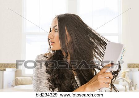 Mixed Race woman brushing hair in bathroom View Large Photo Image Stock Photo - Mixed Race woman brushing hair in bathroom. Fotosearch