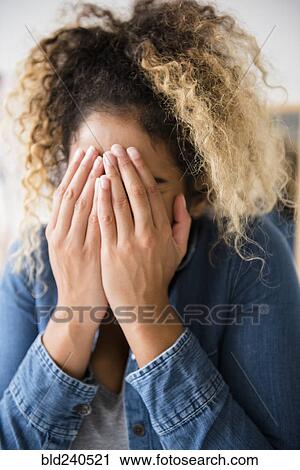Stock Image - Mixed Race woman covering face with hands. Fotosearch