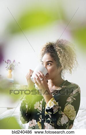Stock Photograph - Mixed Race woman drinking coffee. Fotosearch