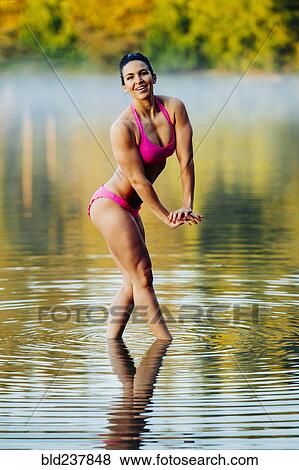 Stock Photo - Mixed Race woman flexing muscles in lake. Fotosearch