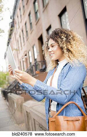 Mixed Race woman in city posing for selfie using digital tablet View Large Photo Image Stock Photo - Mixed Race woman in city posing for selfie using digital tablet. Fotosearch