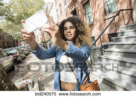 Mixed Race woman in city posing for cell phone selfie View Large Photo Image Stock Photography - Mixed Race woman in city posing for cell phone selfie. Fotosearch