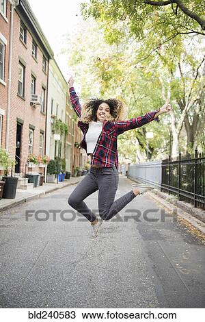 Mixed Race woman jumping for joy in city View Large Photo Image Stock Image - Mixed Race woman jumping for joy in city. Fotosearch