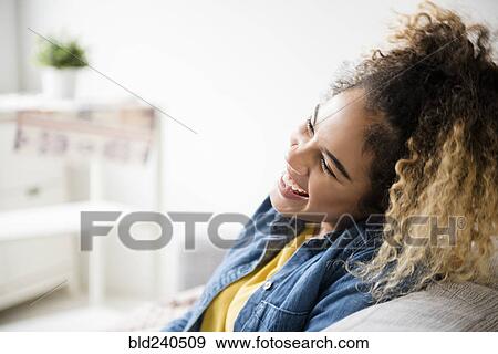 Mixed Race woman laughing on sofa View Large Photo Image Stock Photo - Mixed Race woman laughing on sofa. Fotosearch