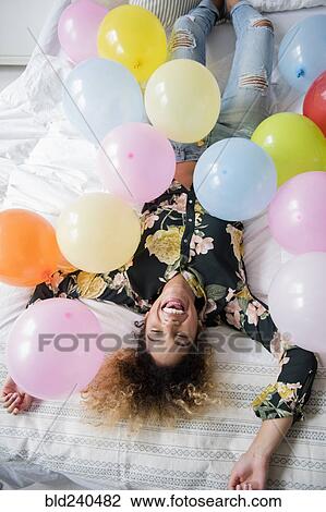 Mixed Race woman laying on bed covered with balloons View Large Photo Image Stock Image - Mixed Race woman laying on bed covered with balloons. Fotosearch