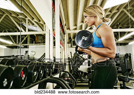 Mixed Race woman lifting barbell in gymnasium View Large Photo Image Stock Photo - Mixed Race woman lifting barbell in gymnasium. Fotosearch