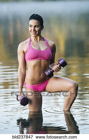 Stock Photo - Mixed Race woman lifting dumbbells in lake. Fotosearch