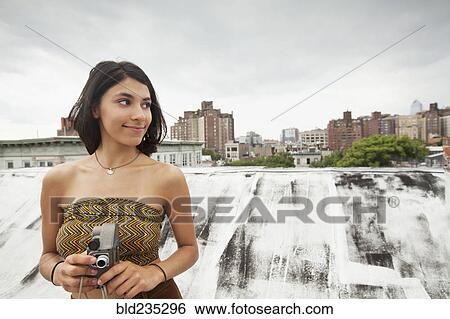 Mixed Race woman on rooftop holding video camera View Large Photo Image Stock Photograph - Mixed Race woman on rooftop holding video camera. Fotosearch
